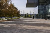 the sidewalk is made from brick and trees are in front of a glass walled building