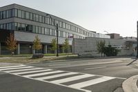 an empty street with two stop lights in front of a building with many windows on it