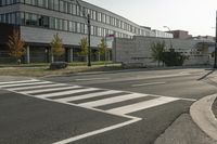 an empty street with two stop lights in front of a building with many windows on it