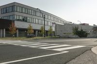 an empty street with two stop lights in front of a building with many windows on it