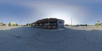 an empty parking lot with buildings in the background of it and a circular shot lens lensed to show a food store