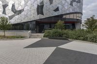 a black paved sidewalk near the entrance to a building with triangles covering the exterior and front