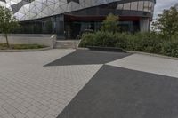 a black paved sidewalk near the entrance to a building with triangles covering the exterior and front