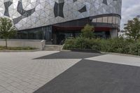 a black paved sidewalk near the entrance to a building with triangles covering the exterior and front