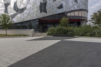 a black paved sidewalk near the entrance to a building with triangles covering the exterior and front