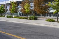 street in front of an office building with trees on both sides of the road and two cars driving down the road