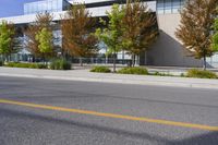 street in front of an office building with trees on both sides of the road and two cars driving down the road