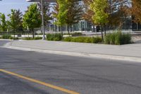 street in front of an office building with trees on both sides of the road and two cars driving down the road