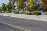 street in front of an office building with trees on both sides of the road and two cars driving down the road