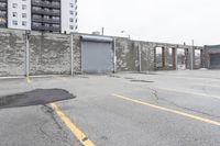 the empty parking lot has only snow on the ground in front of an old brick factory