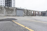 the empty parking lot has only snow on the ground in front of an old brick factory