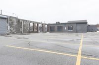 the empty parking lot has only snow on the ground in front of an old brick factory