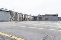 the empty parking lot has only snow on the ground in front of an old brick factory