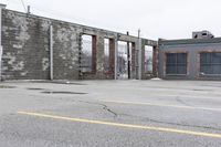 the empty parking lot has only snow on the ground in front of an old brick factory