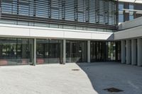 the courtyard in front of a building has several sliding glass doors and a red bench