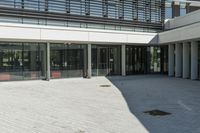 the courtyard in front of a building has several sliding glass doors and a red bench