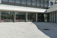 the courtyard in front of a building has several sliding glass doors and a red bench