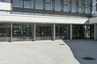 the courtyard in front of a building has several sliding glass doors and a red bench