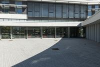 the courtyard in front of a building has several sliding glass doors and a red bench