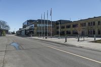 an empty street next to a tall brown building with flags on the sides of it