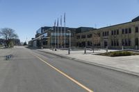 an empty street next to a tall brown building with flags on the sides of it