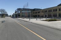 an empty street next to a tall brown building with flags on the sides of it