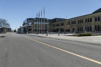 an empty street next to a tall brown building with flags on the sides of it