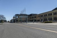 an empty street next to a tall brown building with flags on the sides of it