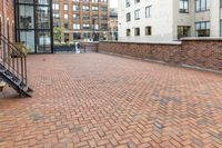red brick floor with two building in the background from top of a roof and on the ground is a brick wall
