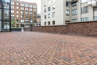 red brick floor with two building in the background from top of a roof and on the ground is a brick wall