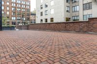 red brick floor with two building in the background from top of a roof and on the ground is a brick wall