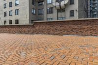 red brick floor with two building in the background from top of a roof and on the ground is a brick wall