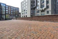 red brick floor with two building in the background from top of a roof and on the ground is a brick wall