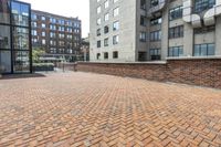 red brick floor with two building in the background from top of a roof and on the ground is a brick wall