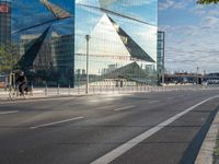 a sign stands on the corner of a paved street in front of a building with a triangle shaped glass structure