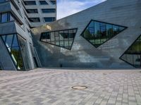 an open courtyard with multiple windows and a circular hole in the ground near buildings with geometric shapes