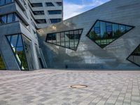 an open courtyard with multiple windows and a circular hole in the ground near buildings with geometric shapes