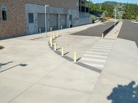 several yellow poles standing in a driveway next to a parking garage on an industrial day