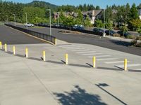 several yellow poles standing in a driveway next to a parking garage on an industrial day