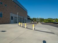 several yellow poles standing in a driveway next to a parking garage on an industrial day