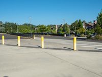 several yellow poles standing in a driveway next to a parking garage on an industrial day