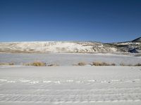 a woman is standing in the snow near the hills with her snowboard on their feet