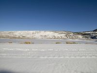 a woman is standing in the snow near the hills with her snowboard on their feet