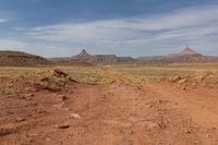 an arid dirt road and a mountain in the distance with rocks on either side of it