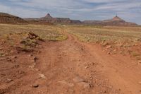 an arid dirt road and a mountain in the distance with rocks on either side of it