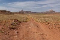 an arid dirt road and a mountain in the distance with rocks on either side of it