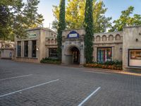 there is a tall building with trees outside it that has a brick sidewalk next to the entrance