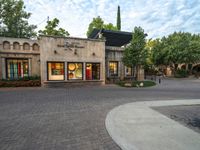 there is a tall building with trees outside it that has a brick sidewalk next to the entrance