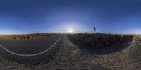 a split down road near a field at sunset in the desert with a lone object on the top