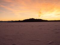 an orange sunset over the mountains and snow covered field at sunrise in winter time in arizona